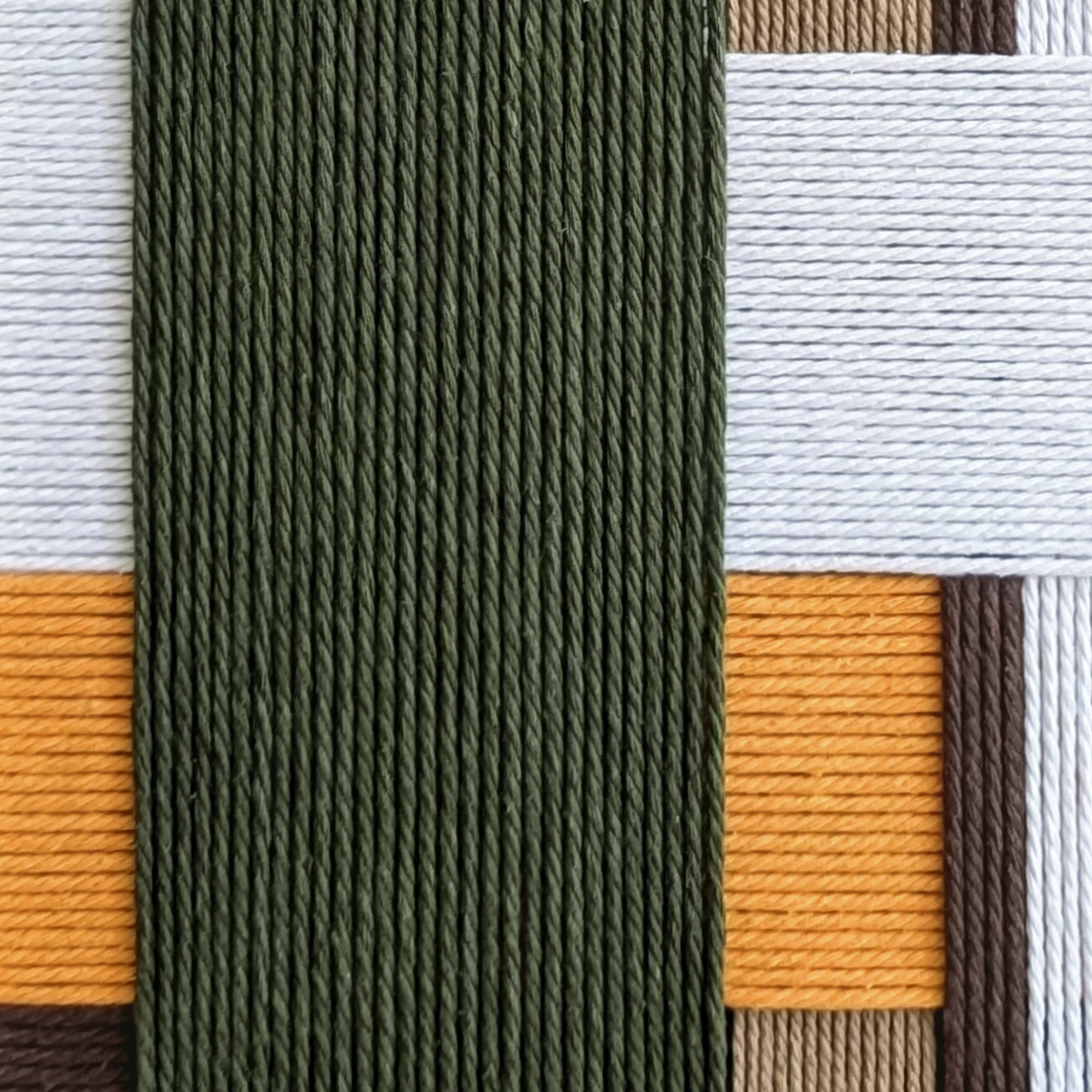 תקריב של אריגת חוטי כותנה בגווני לבן, חום, חום כהה, ירוק זית וכתום חלמון