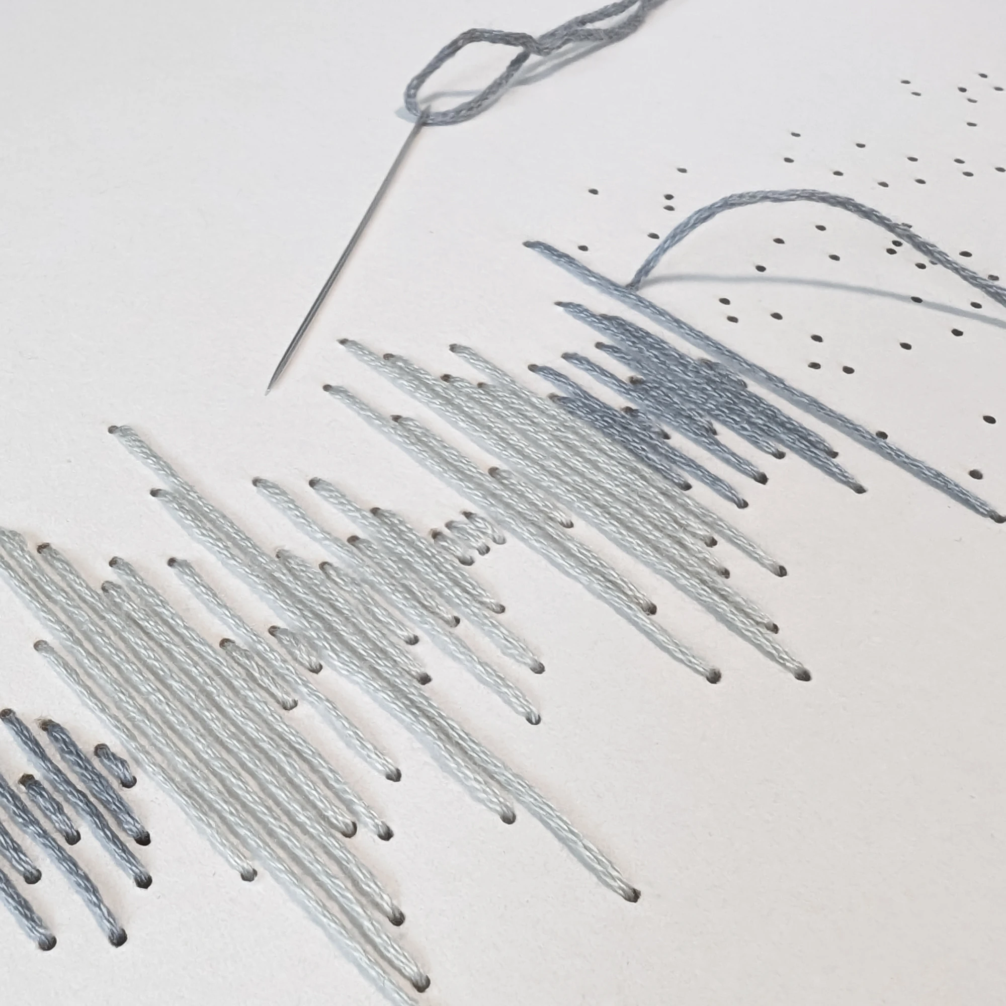 תקריב של רקמת כותנה של פסקול הקלטה אישית בגווני אפור עם מחט רוקמת