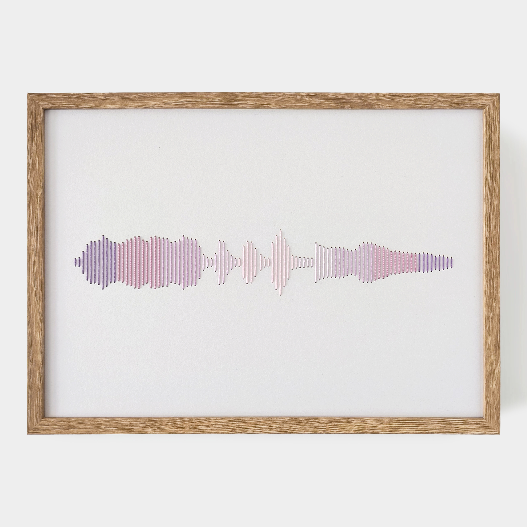 רקמת כותנה בגווני ורוד וסגול של פסקול הקלטה אישית, ממוסגרת במסגרת עץ