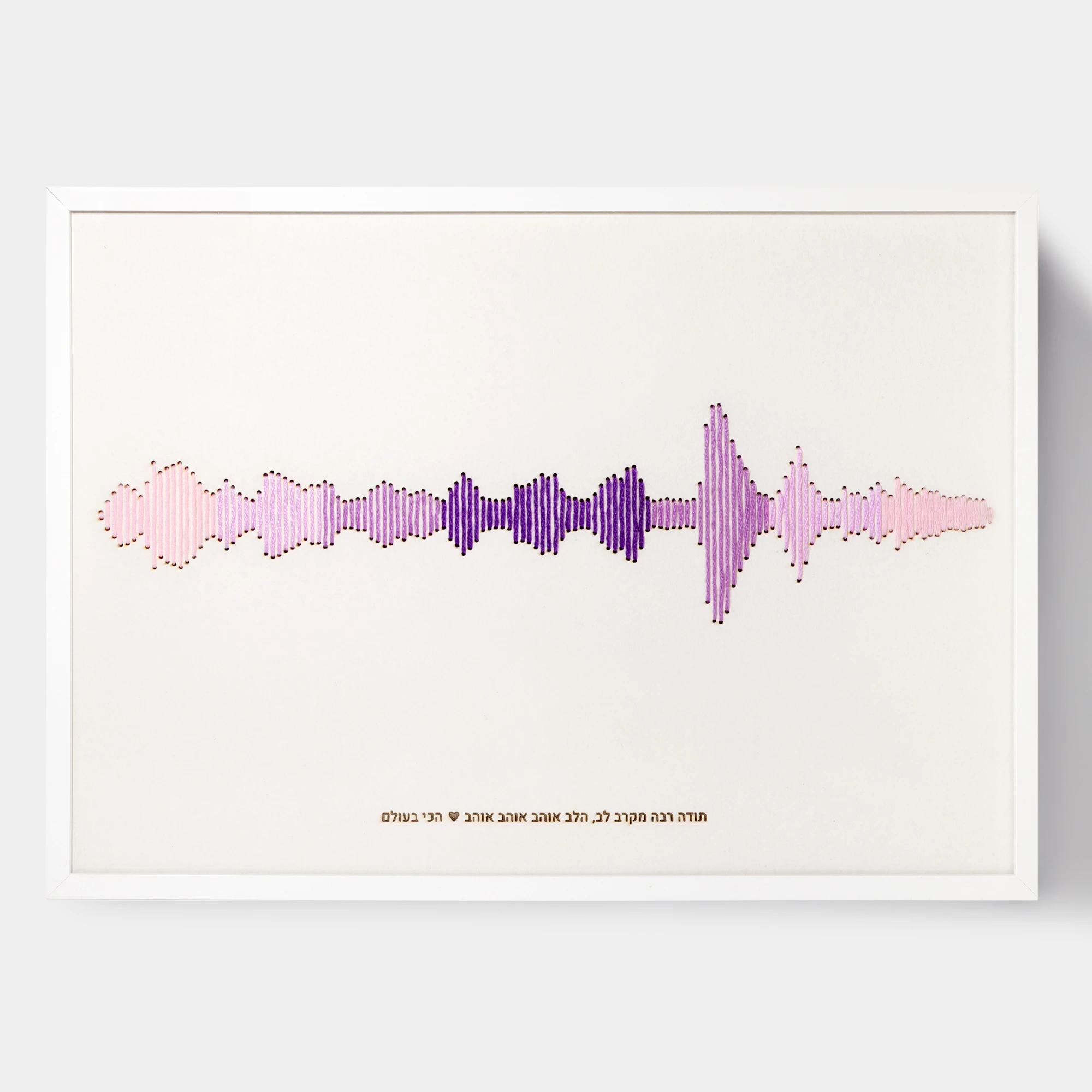 רקמת כותנה בגווני ורוד וסגול של פסקול הקלטה אישית, ממוסגרת במסגרת לבנה עם חריטת טקסט בתחתית
