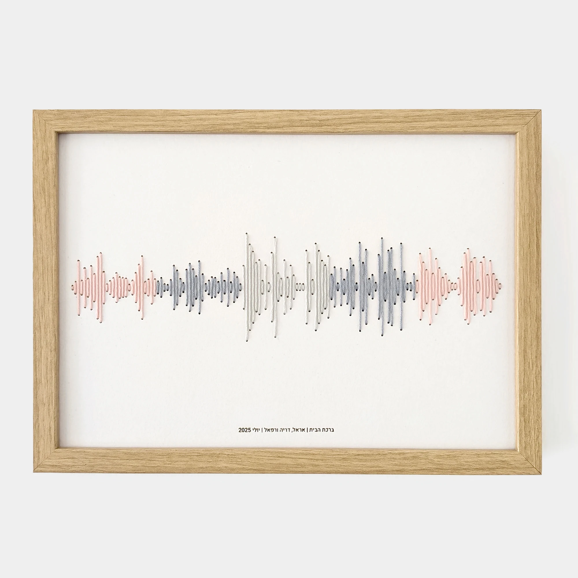 רקמת כותנה בגווני ורוד ואפור של פסקול הקלטה אישית, ממוסגרת בעץ עם חריטת טקסט בתחתית