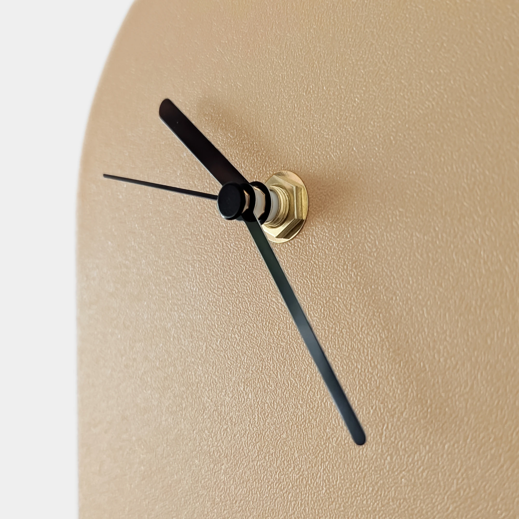 תקריב של שעון אובלי בהדפסת תלת מימד בצבע חום בהיר עם מחוגים שחורים