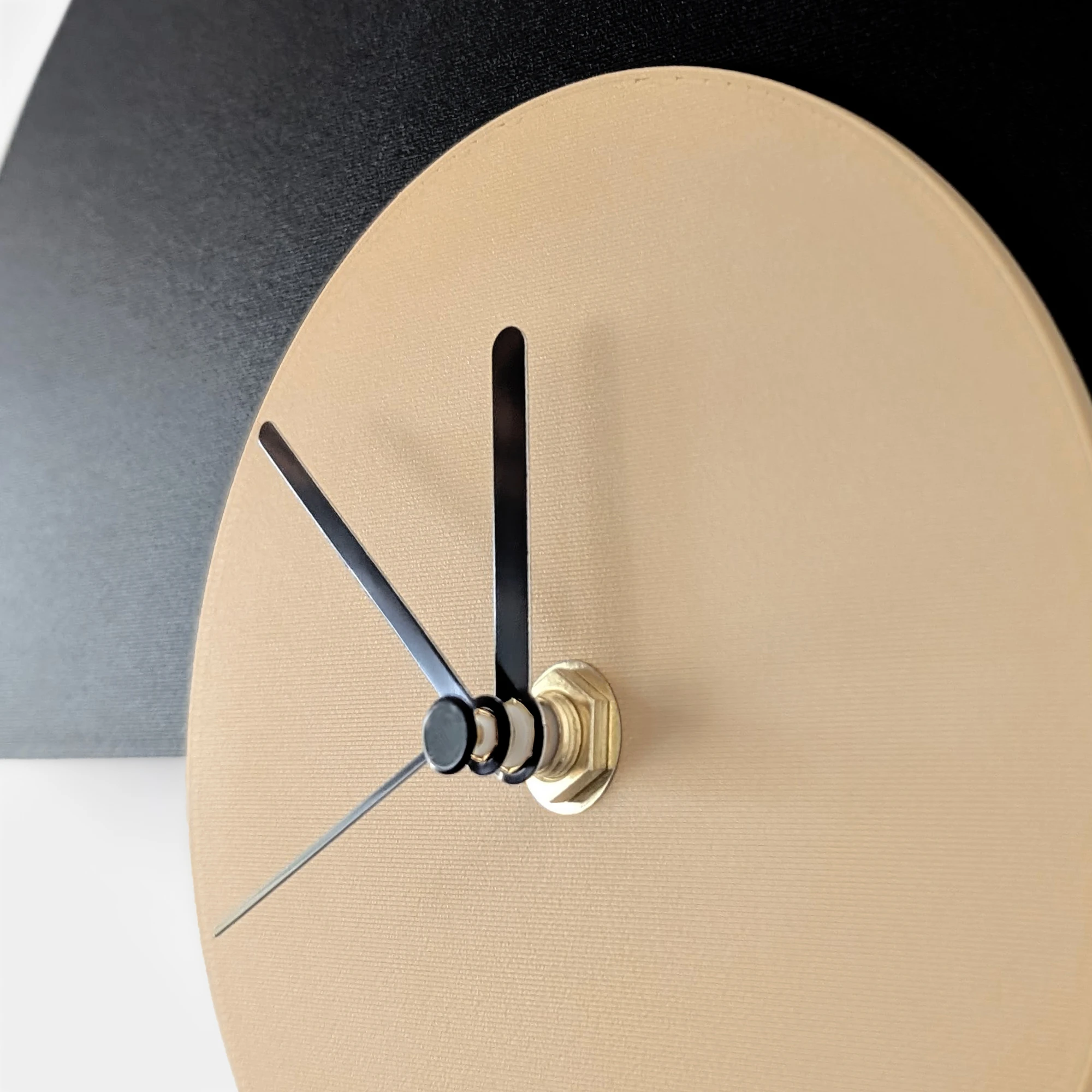 תקריב של שעון גיאומטרי בהדפסת תלת מימד בצבעי שחור, חום בהיר ומחוגים שחורים