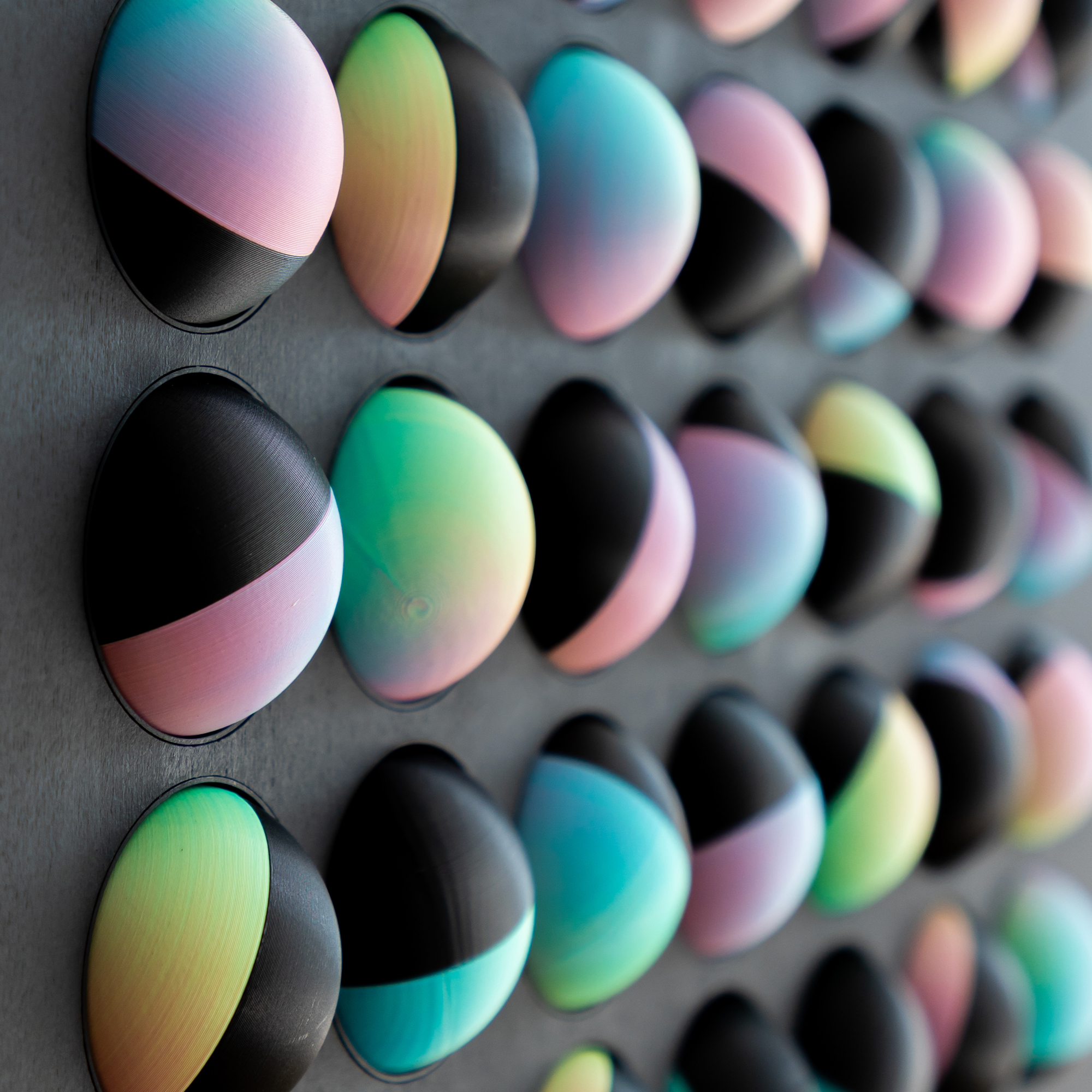 תקריב של כדורים בהדפסת תלת מימד בצבעי שחור וטריקולור פסטל